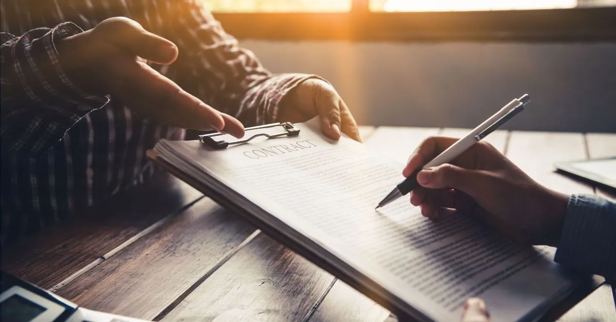 A businessperson signing a contract with a client, discussing the outstanding DEWA bill from a previous tenant in Dubai