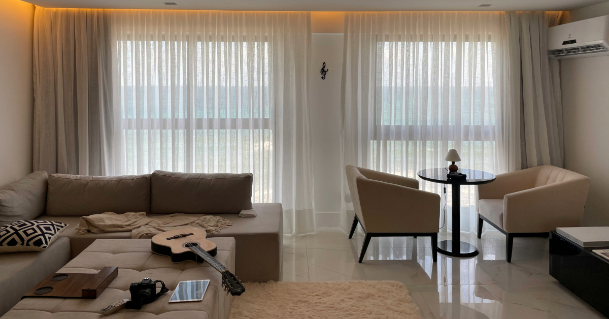 A living room with a sofa, a dining table, and a guitar placed on the sofa