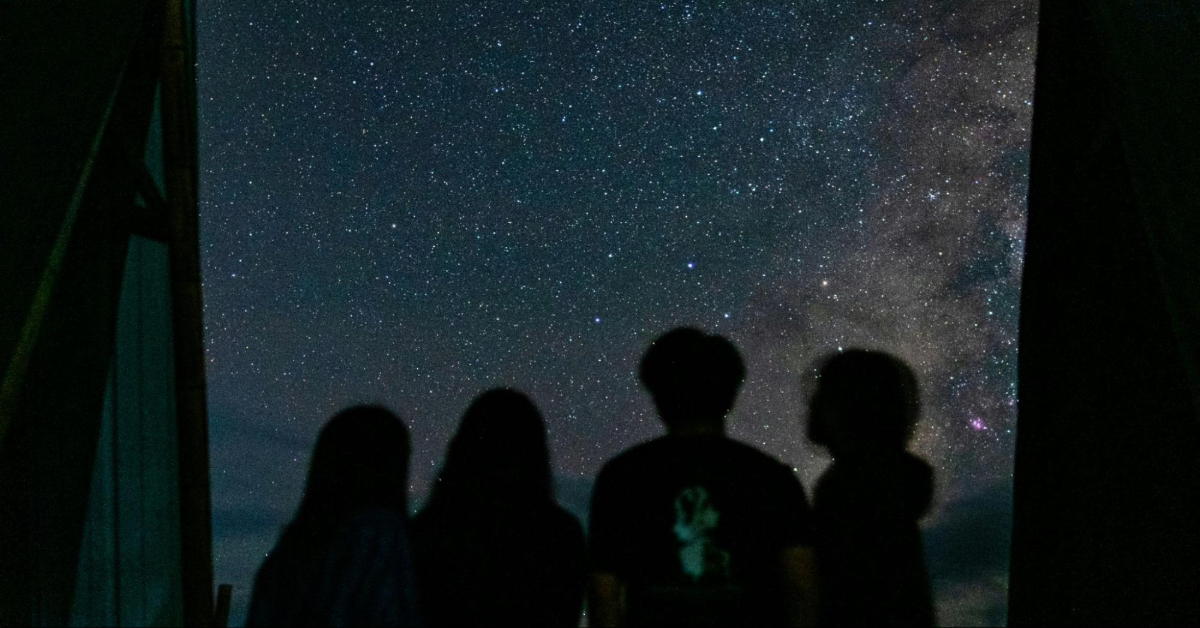 Friends stargazing under the open sky on a chilly night