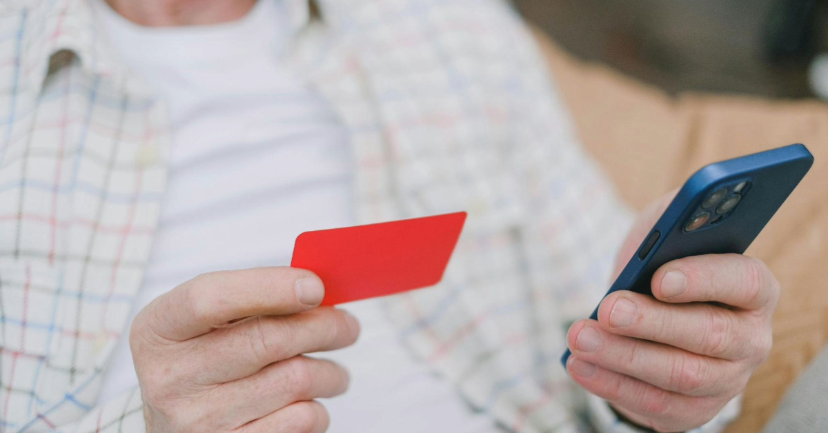 Close-up of a senior adult handling a card and smartphone for online payment