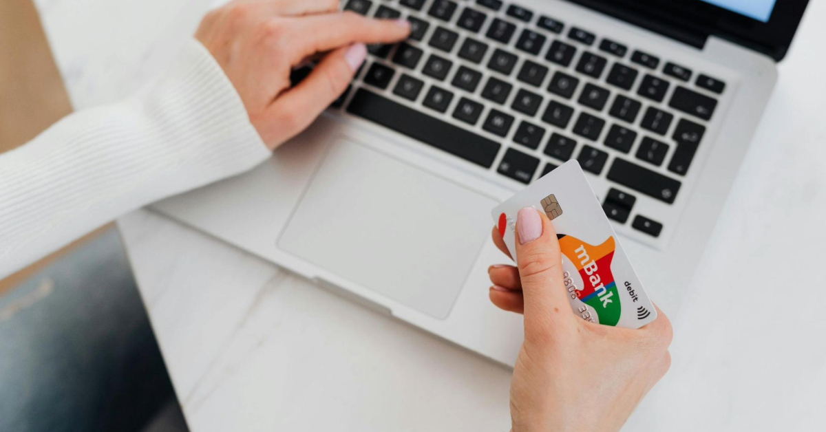 Close-up of a person using a laptop and holding a credit card for online shopping