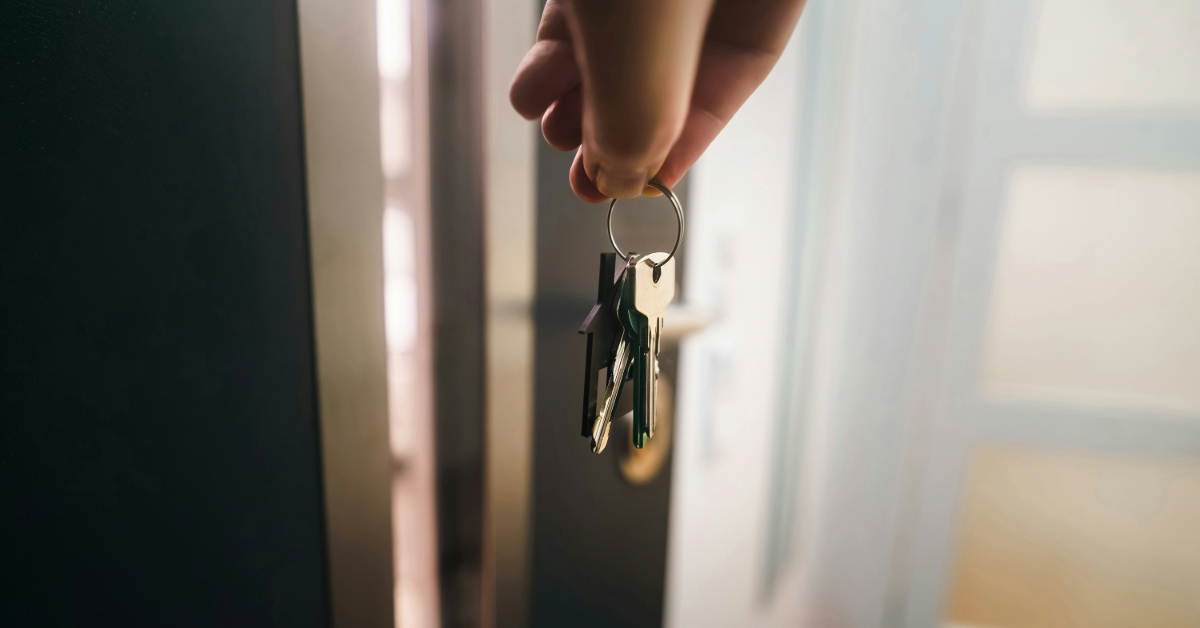 A hand holding keys near a door