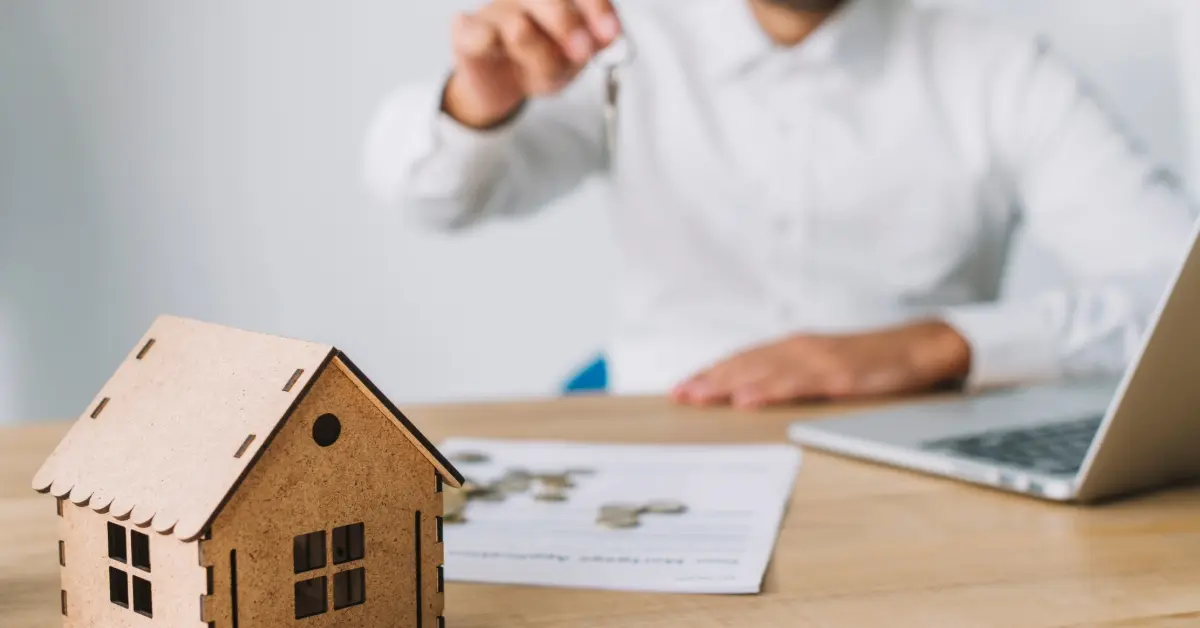 صورة مجسم منزل صغير ورجل يمسك بمفتاح منزل