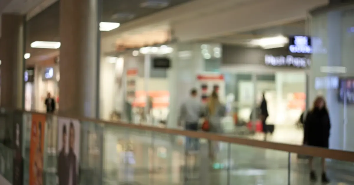 A blurry wide shot of the interior of a large modern shopping mall&nbsp;