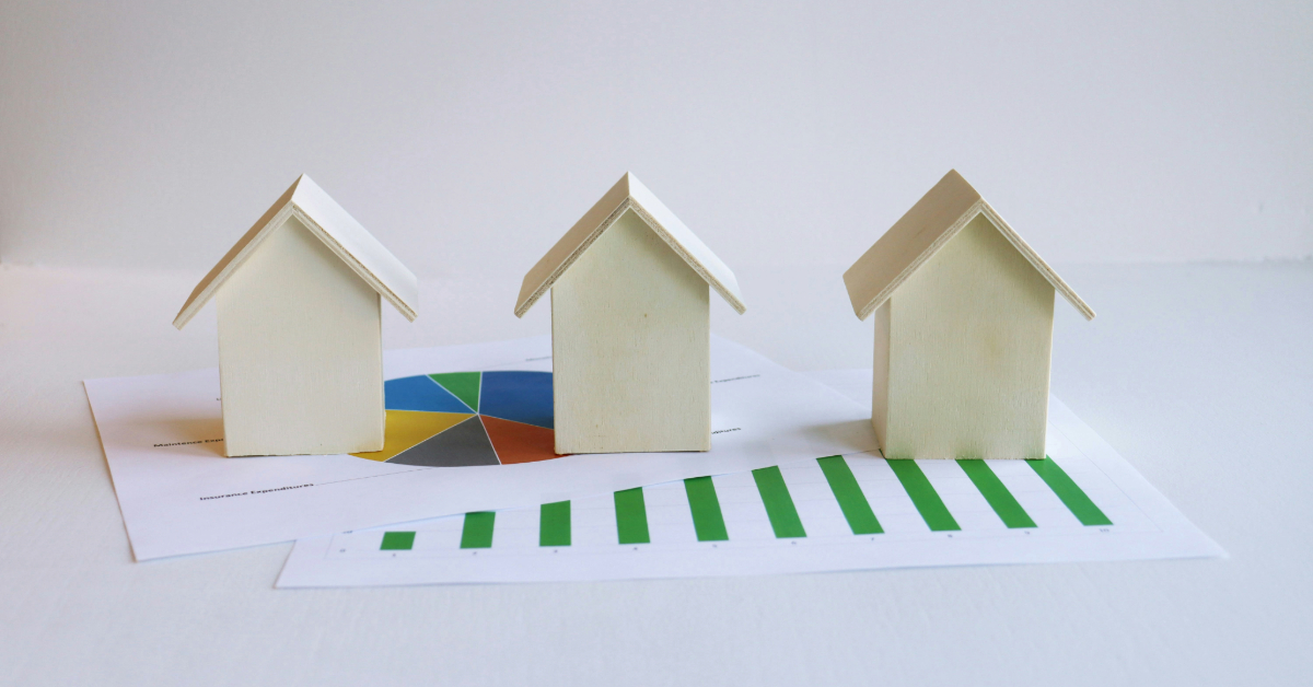 Three identical miniature house models placed on a table on top of a graph sheet