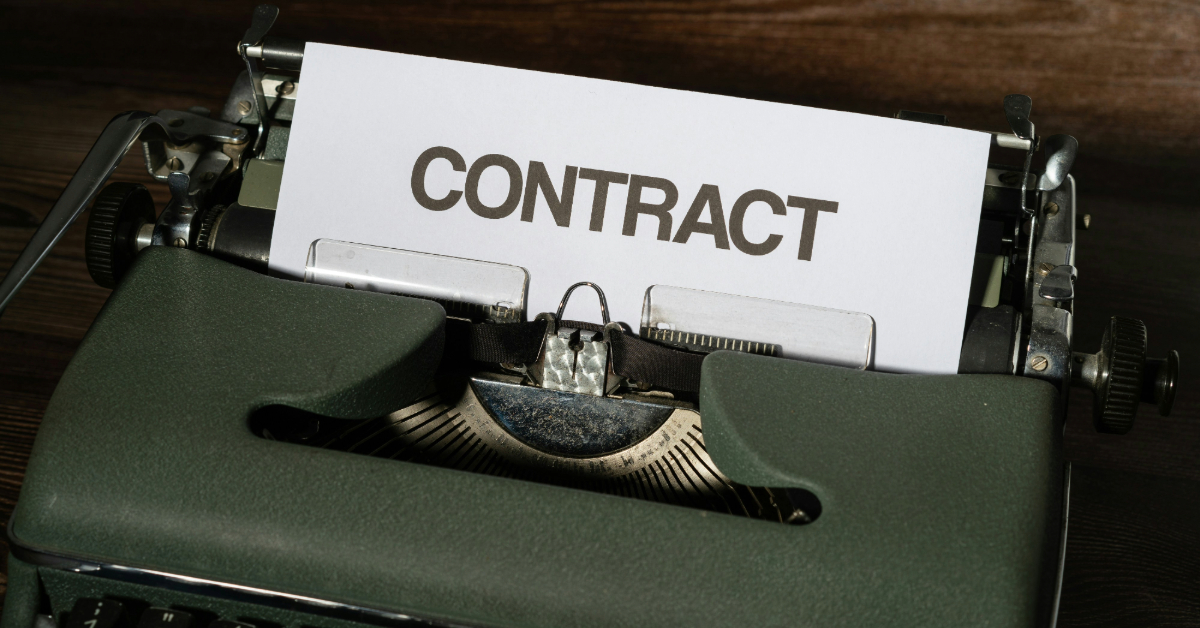 A typewriter typed the word “contract” on a sheet of paper