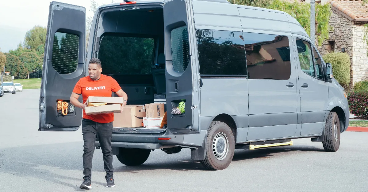صورة توضح رجل يعمل في شركة توصيل أثناء توصيل الطرود