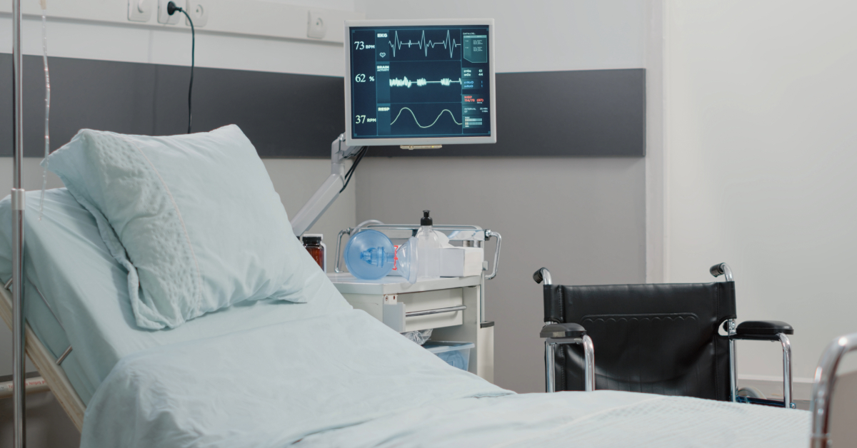 An empty hospital bed with a wheelchair beside it