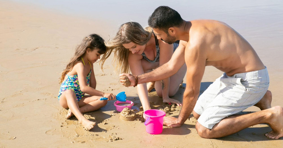 Parents helping their daughter build a sand castle on the beach