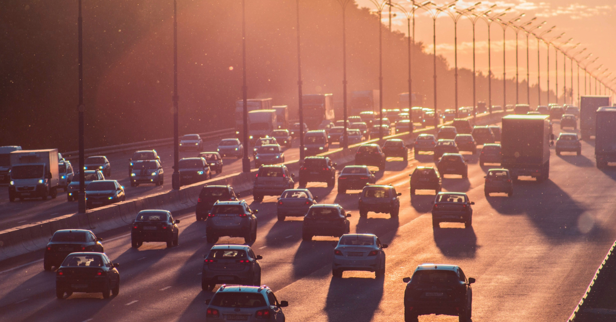 Many cars driving along a highway at sunset