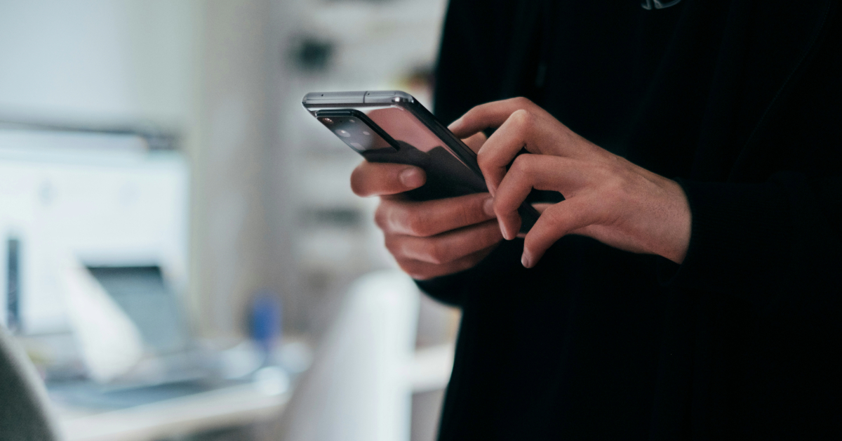 A person scrolling through their phone behind a desk