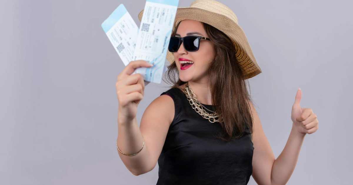 A happy woman holding tickets and giving a thumbs-up