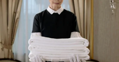 A maid Holding a Stack of Towels