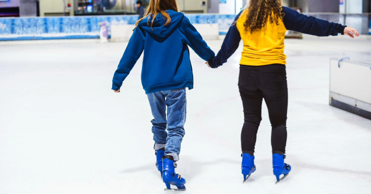 Two best friends skating together, enjoying the ice side by side