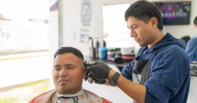 A man getting a haircut in one of the best barber shops in Sharjah