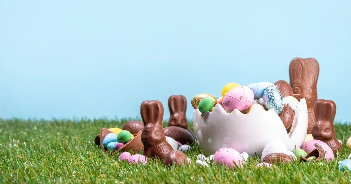 Colourful Easter eggs arranged on green grass with spring flowers
