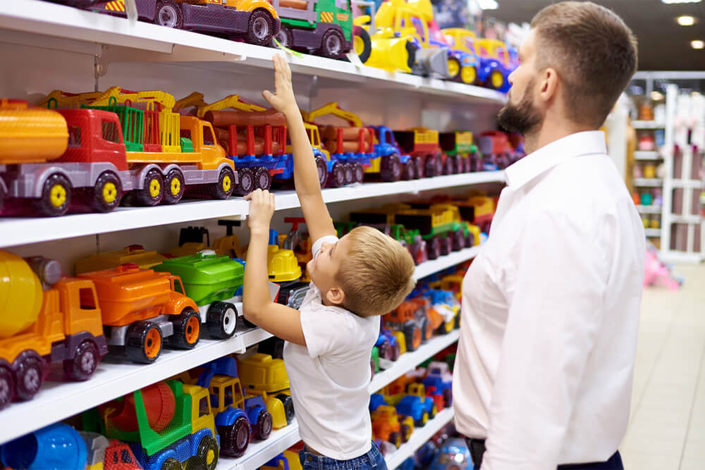 A boy selecting a toy car with a parent