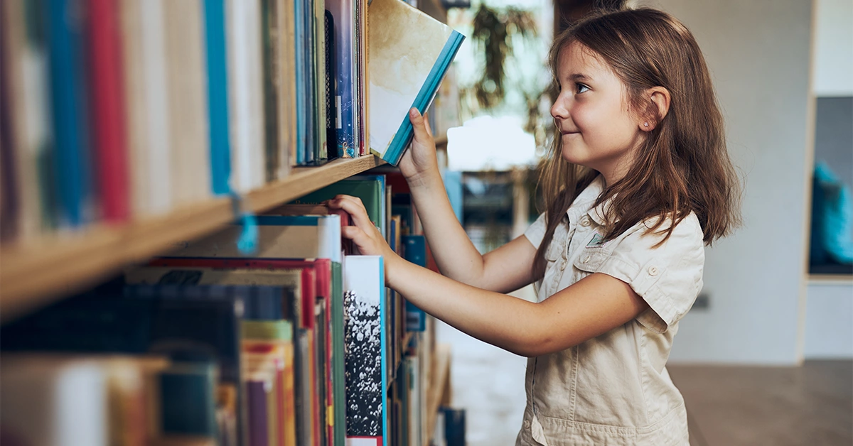 A student choosing a book in Gems Jumeirah Primary School Library 