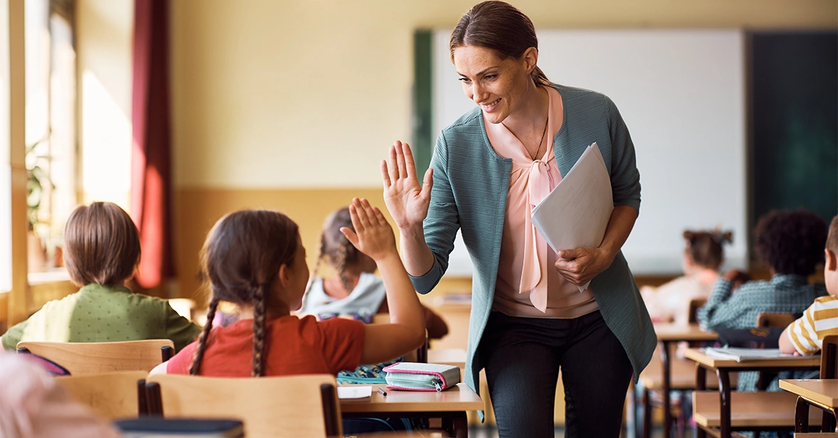 school teacher giving a high-five to a student
