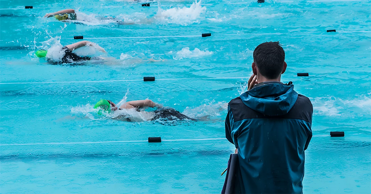 male swimming coach standing by the swimming pool