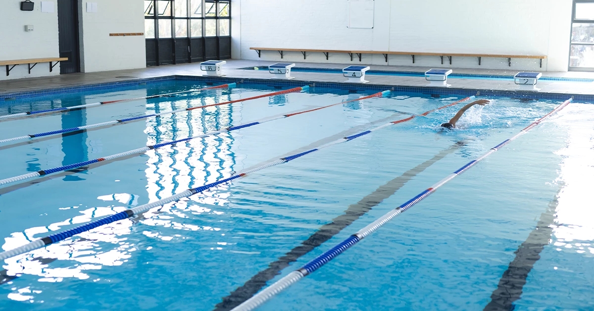 A swimmer practices in an indoor pool at a sports facility in Sharjah