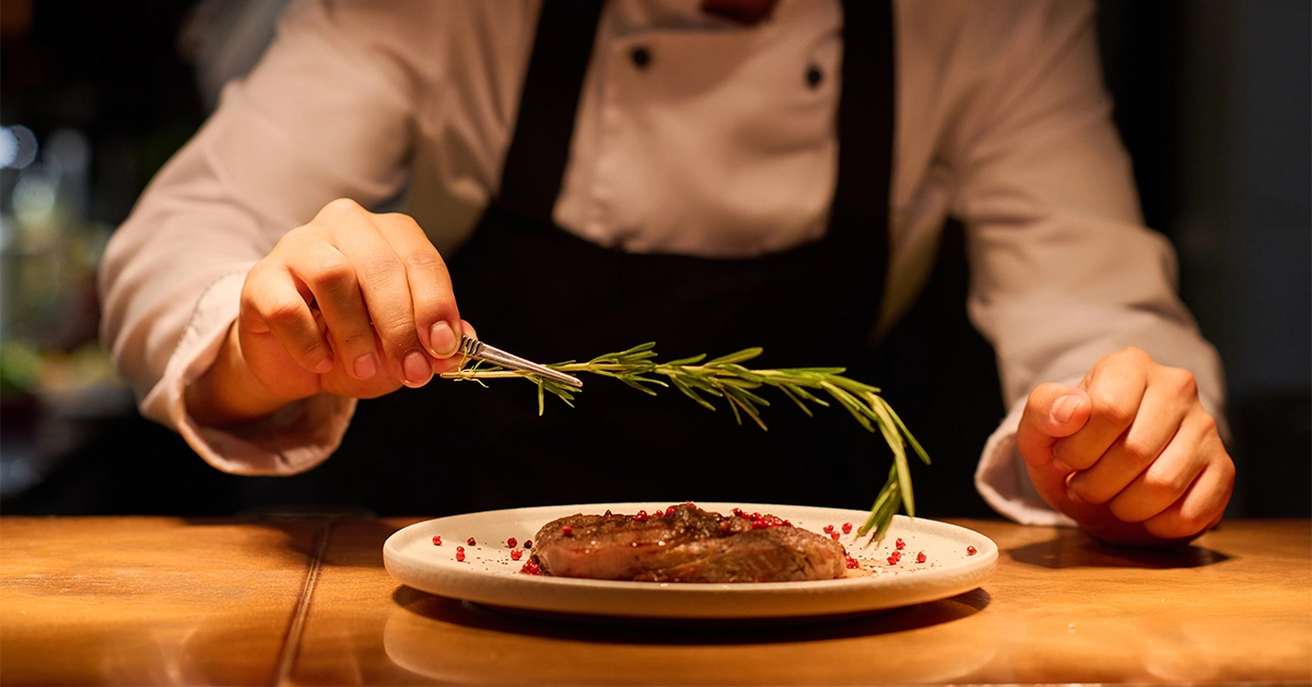 waiter serving steak in The Grill restaurant