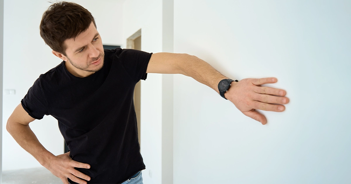 A man looking for defects in the wall of an apartment