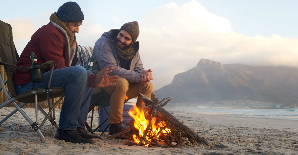 Two Friends sitting around a bonfire on the beach
