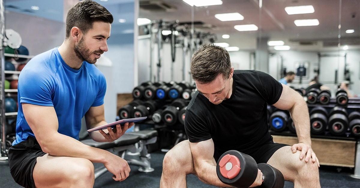 A trainer guiding a man in a gym in Al Ain