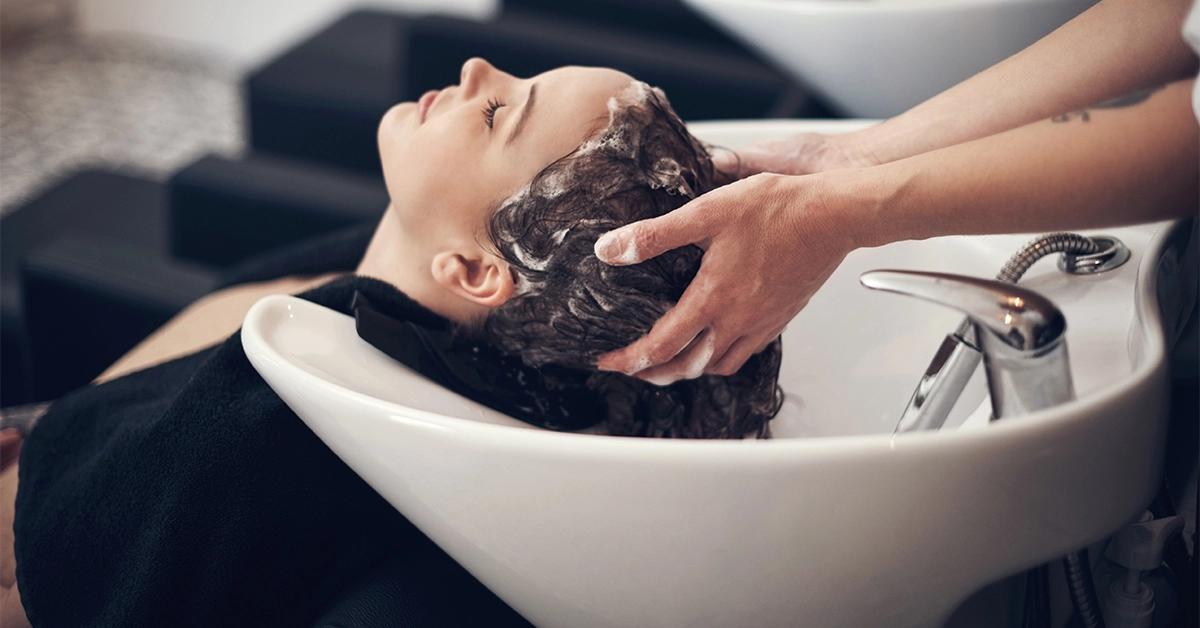 Hairdresser washing client’s hair in salon