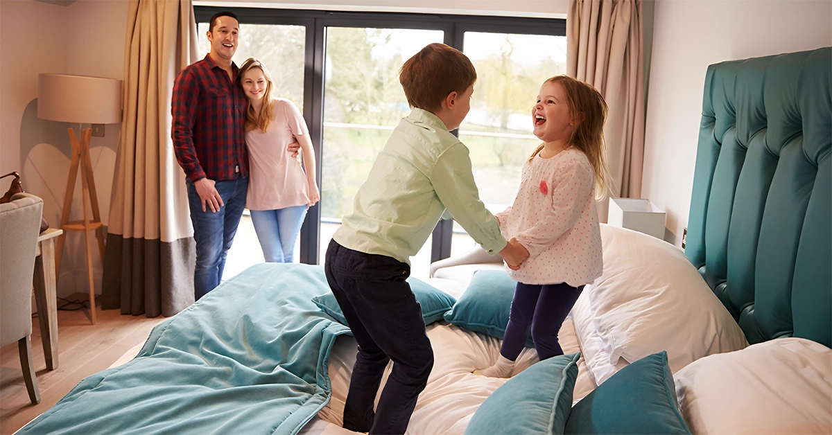 Kids jumping on plush bedding in a hotel room
