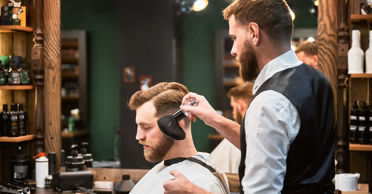 A hairdresser trimming a client's beard