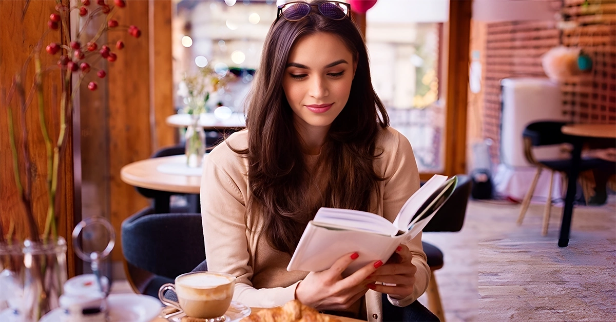 A woman reading a book with a coffee at one of the best cafes in Khalifa City