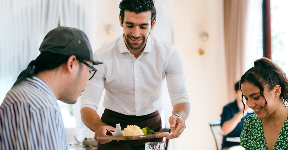 A waiter serving food to a couple