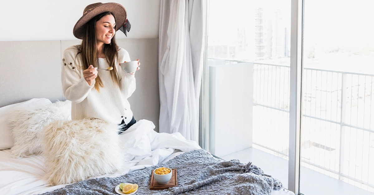 A young tourist enjoying a healthy breakfast in her hotel room 