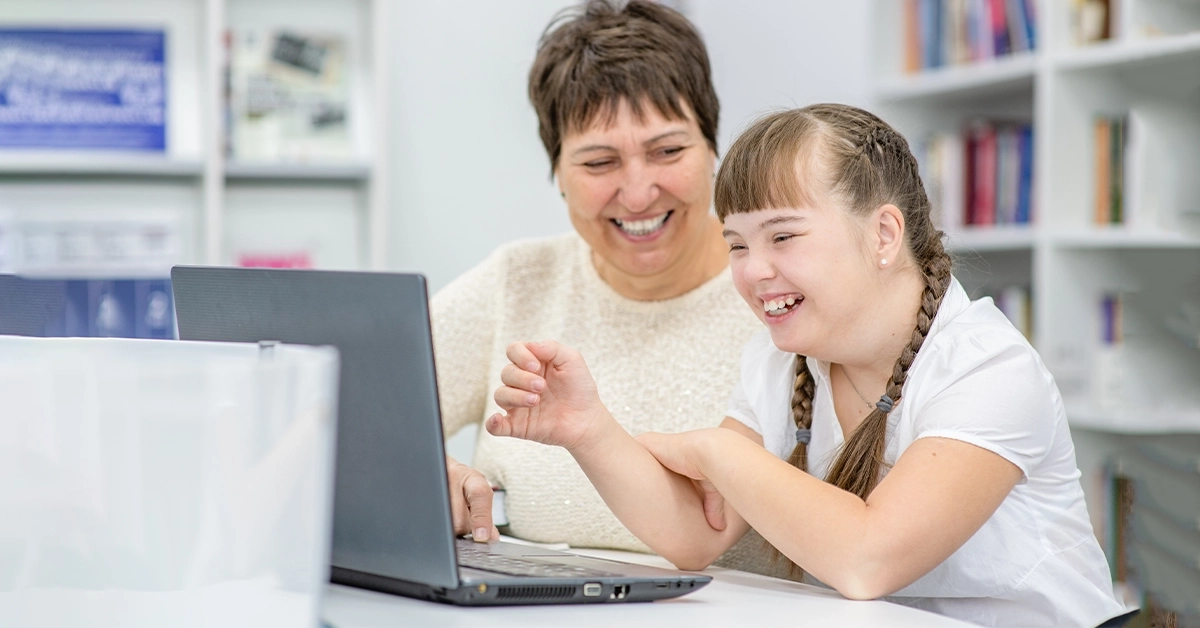 A girl with Down syndrome working on a laptop