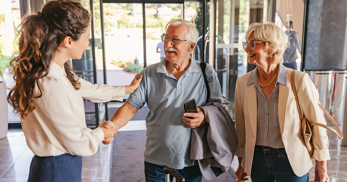 A hotel staff welcoming an elderly couple