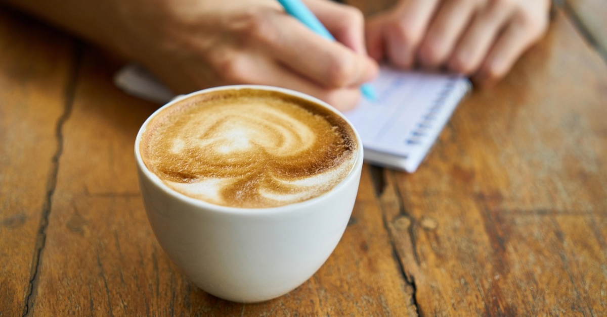 Coffee in a coffee shop with a man writing on a notebook 