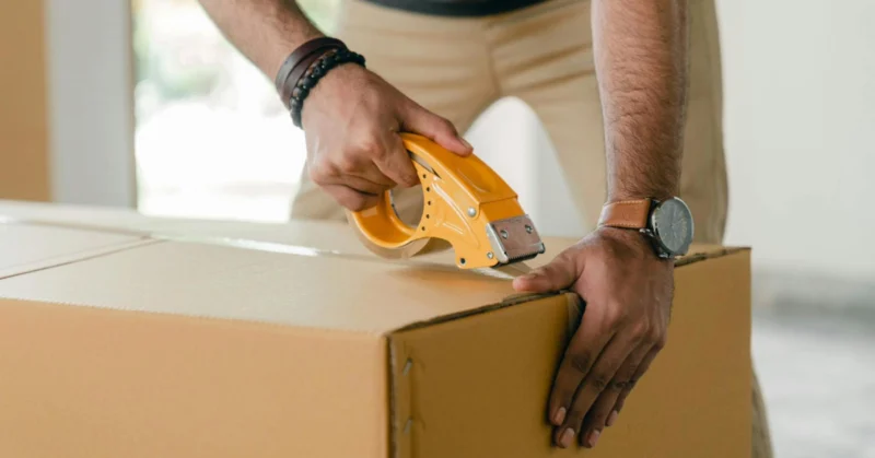 man wrapping up a box to move out
