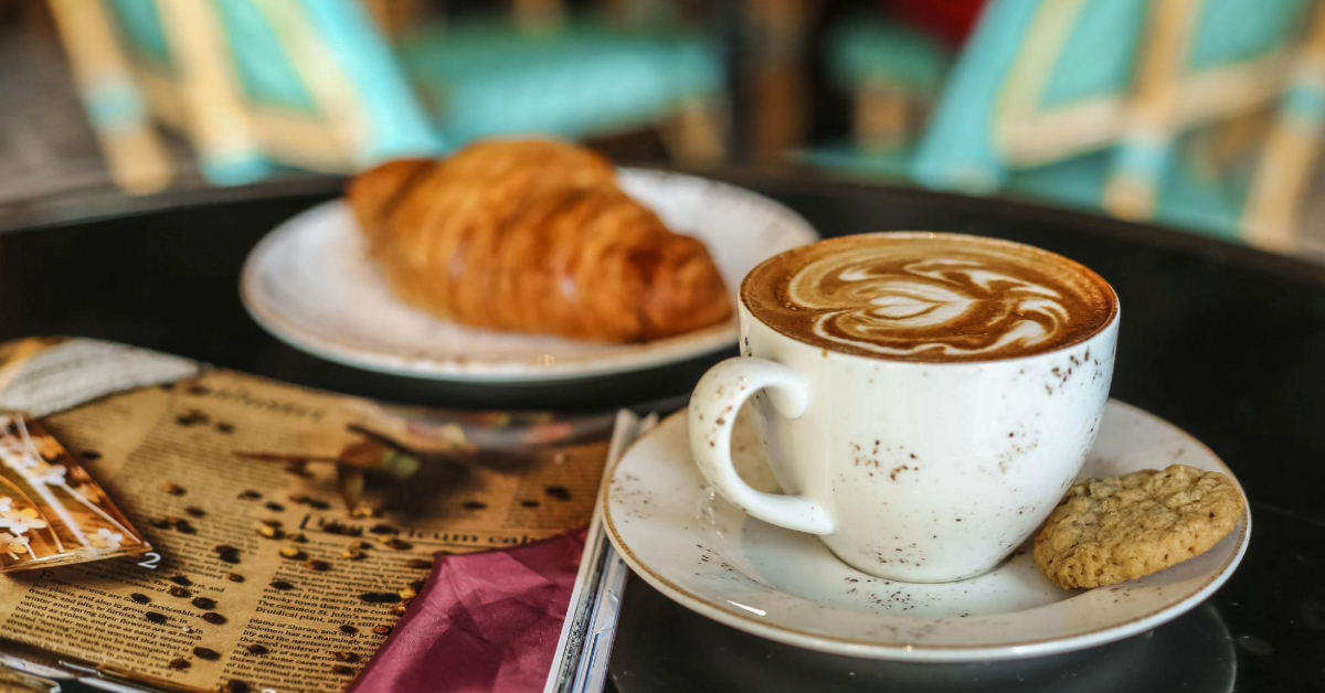 صورة فنجان قهوة وكروسان على طاولة مقهى