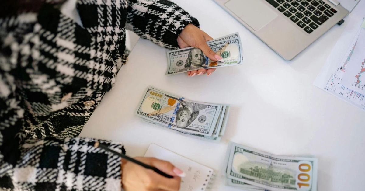 A person counting stacks of hundred-dollar bills - cost of living dubai