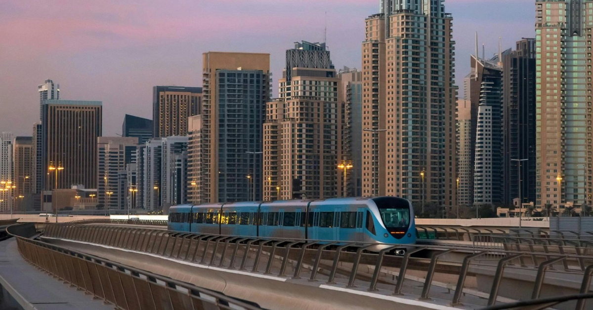 Dubai metro moving along elevated tracks with dubai skyscrapers in the background during sunset