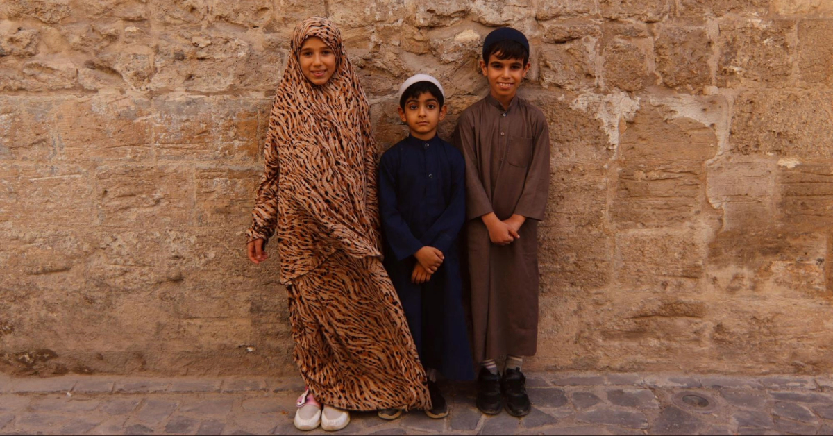 Kids standing in front of a historic wall in the Kalba heritage village