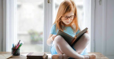 Little girl reading a book in a nursery near Barsha Heights