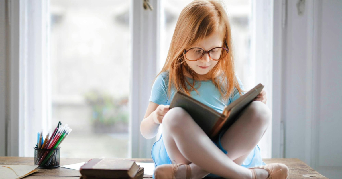 Little girl reading a book in a nursery near Barsha Heights