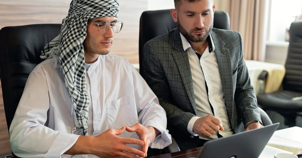 Man in White Thobe Sitting Beside Man in Gray Suit