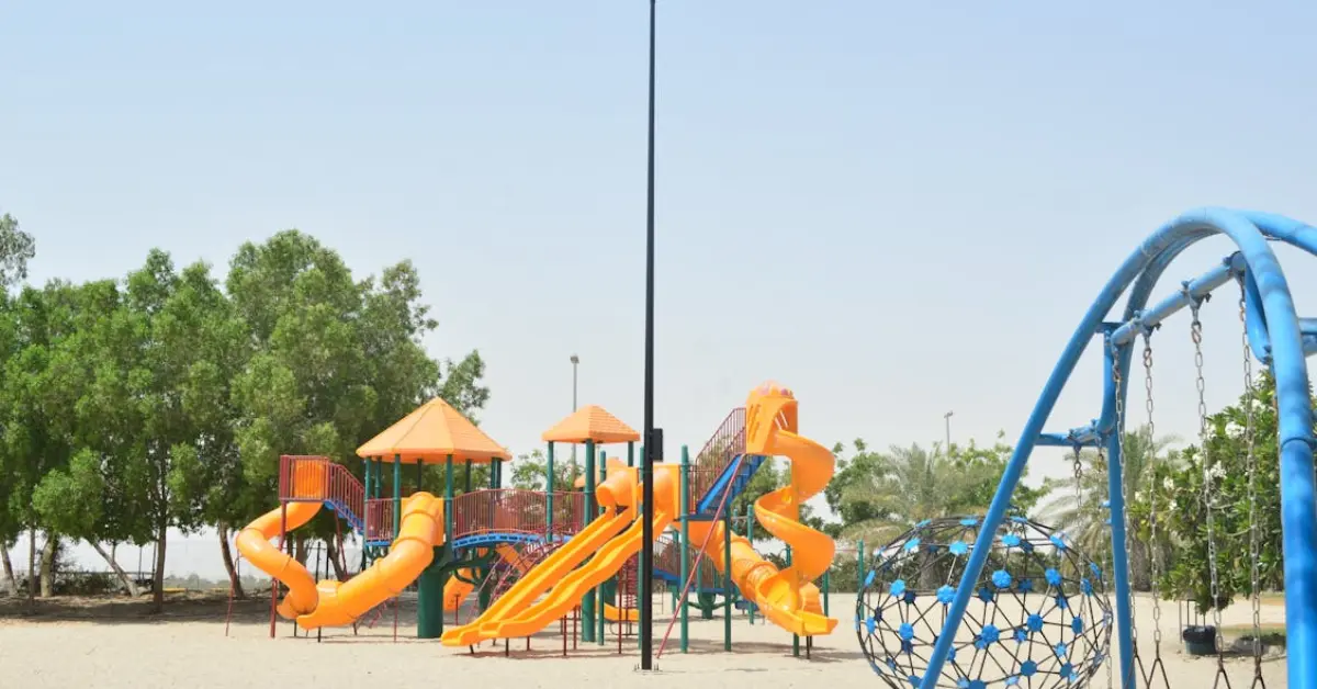 Outdoor playground in Abu Dhabi with orange slides, a blue climbing structure, and a clear sky