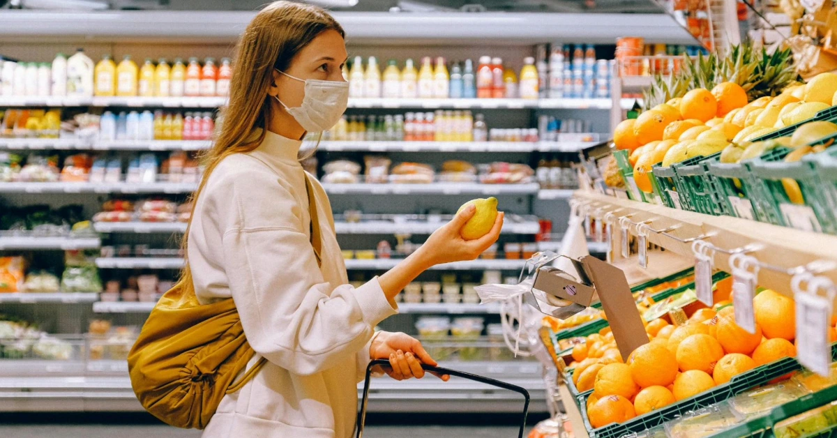 Woman in mask shopping for fruit in a supermarket