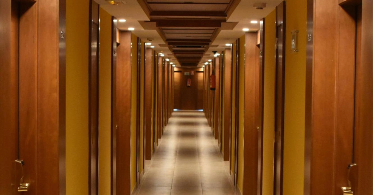 Wooden hotel corridor with warm lighting and neatly aligned room doors
