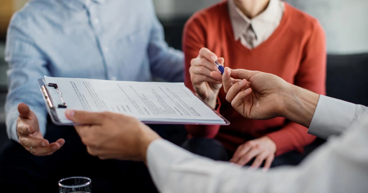 Closeup of couple signing a contract with insurance advisor